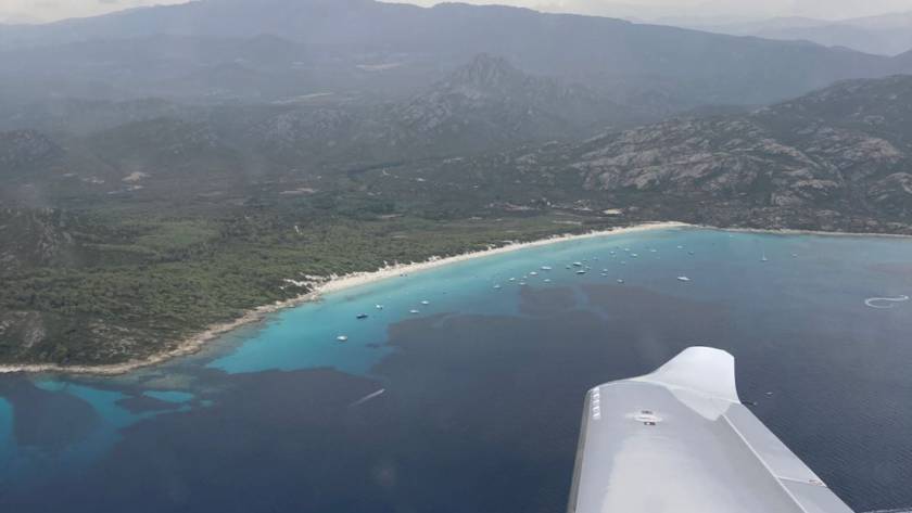 Vue aérienne d'un port pittoresque et d'une plage magnifique lors d'un vol Instant'Air entre Montpellier et Figari. Un exemple de la beauté que les membres peuvent découvrir lors de leurs voyages d'affaires avec Instant'Air.